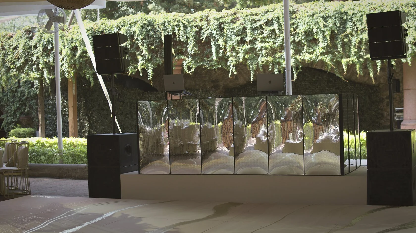 Cabina de DJ con espejos y sistema de audio line array montados para una boda en jardín