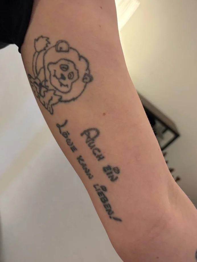 Altes Bär-Tattoo mit Schriftzug am Unterarm vor dem Cover-Up