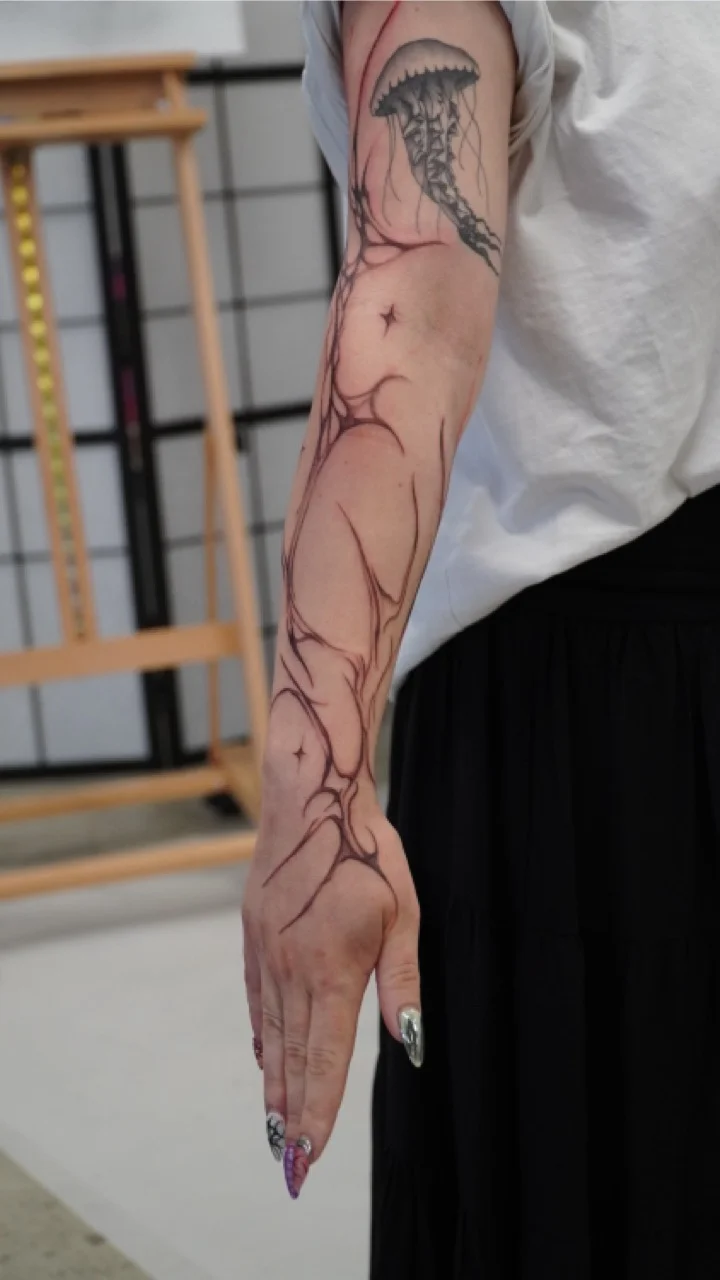 Feines Freehand-Tattoo, das dem Verlauf des Unterarms folgt