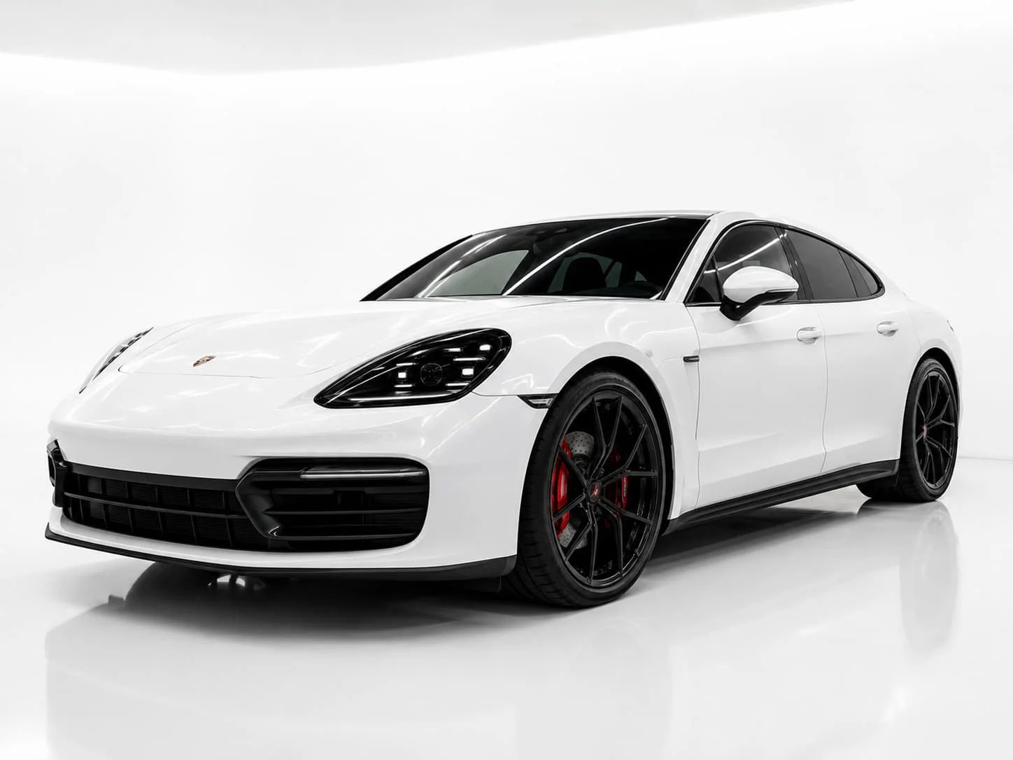 Full white sports sedan in a clean white studio