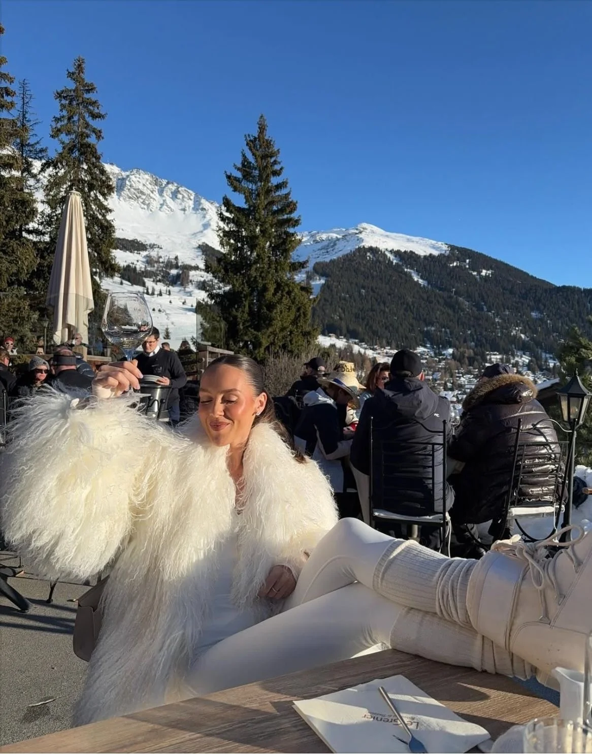 A woman in a white fur coat on a sunny terrace