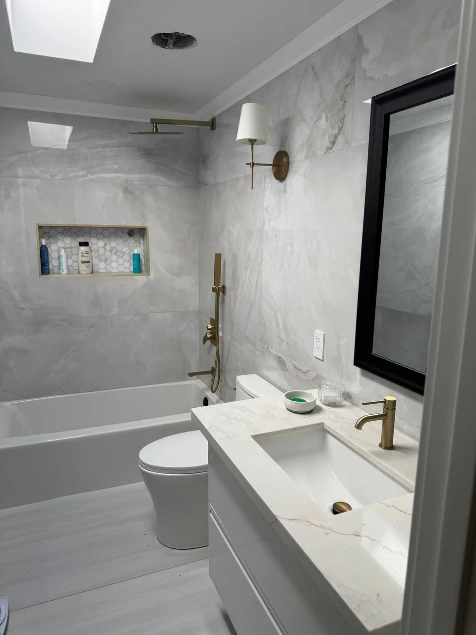 Marble bathroom with brass fixtures and tiled niche