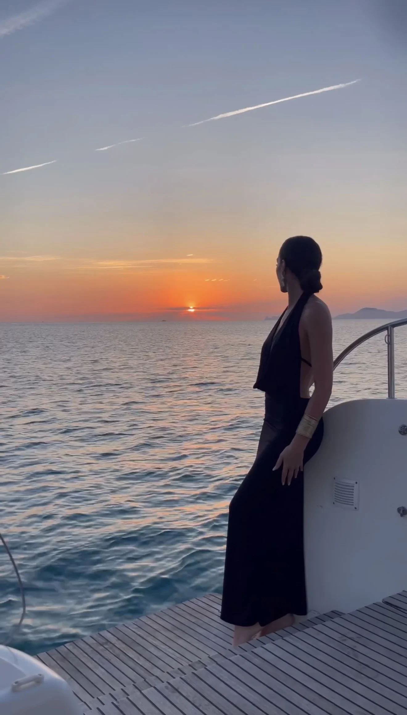 Woman on a boat watching the sunset over the sea