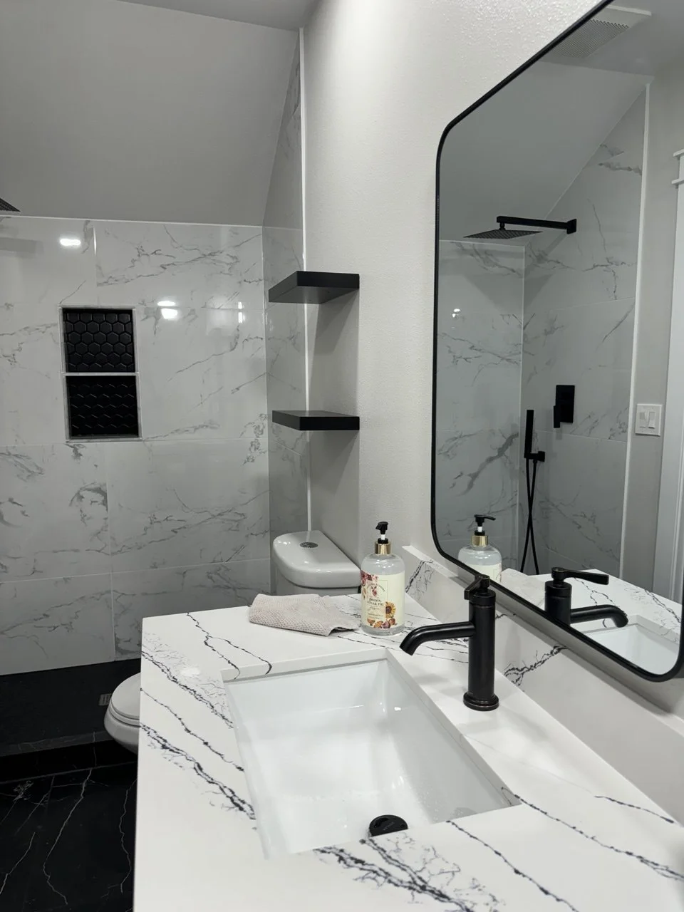 Marble shower with matte black trim and corner shelves